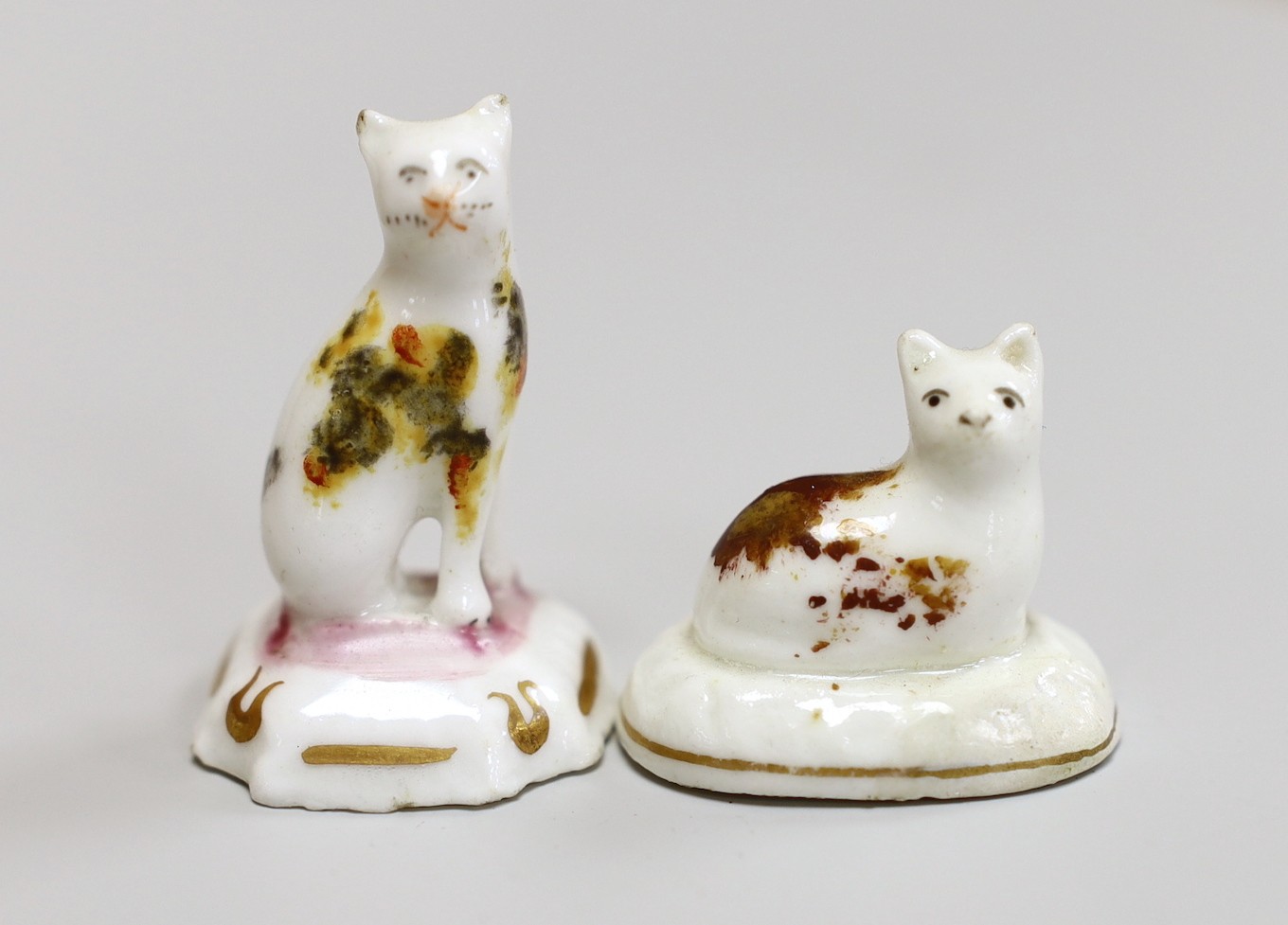 A seated toy Staffordshire cat with tortoiseshell markings, together with a Staffordshire recumbent toy cat with brown markings, c.1830-50, tallest 4cm., Cf. Dennis G.Rice Cats in English porcelain, colour plate 57., Pro